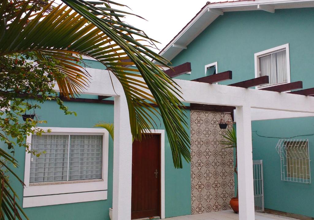 una casa azul con una puerta roja y una palmera en Casa Açores Residencial - Apartamentos Praia dos Ingleses Floripa SC, en Florianópolis