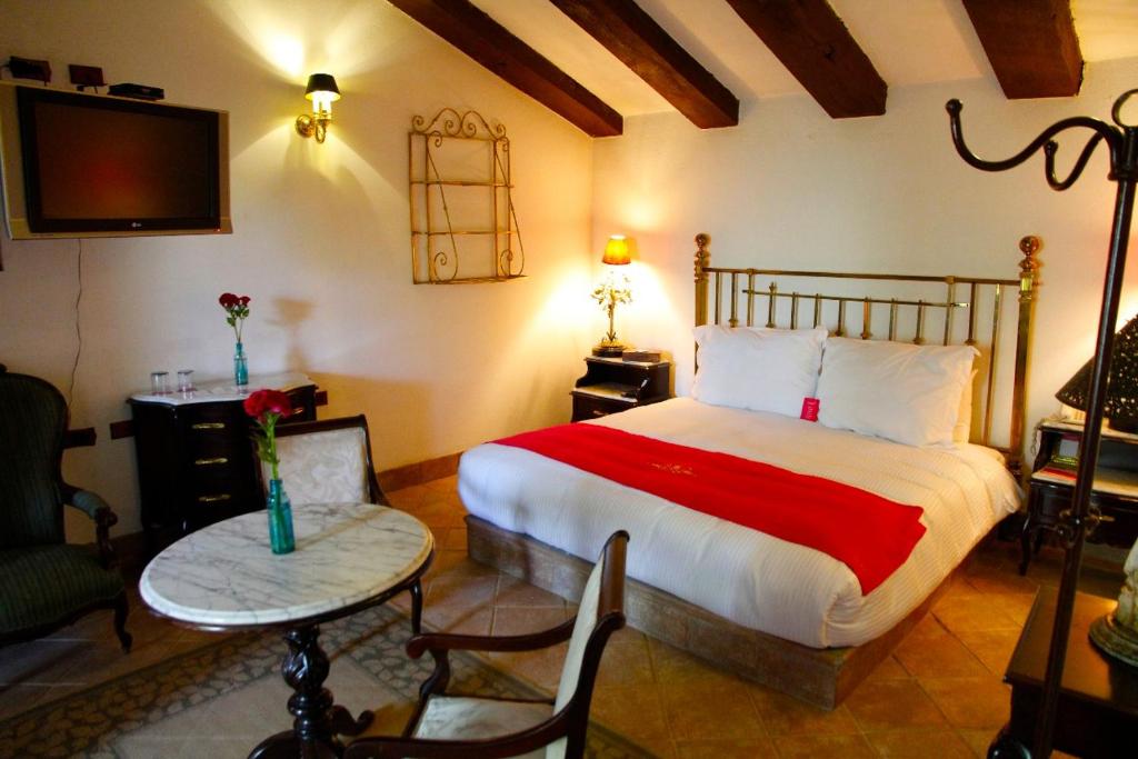 een slaapkamer met een bed en een tafel en een televisie bij Las Calandrias in Atlixco