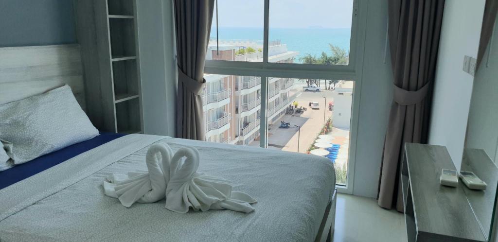 ein Schlafzimmer mit einem weißen Häschen auf einem Bett mit einem Fenster in der Unterkunft Grandblue condominium Room 606 in Mae Pim