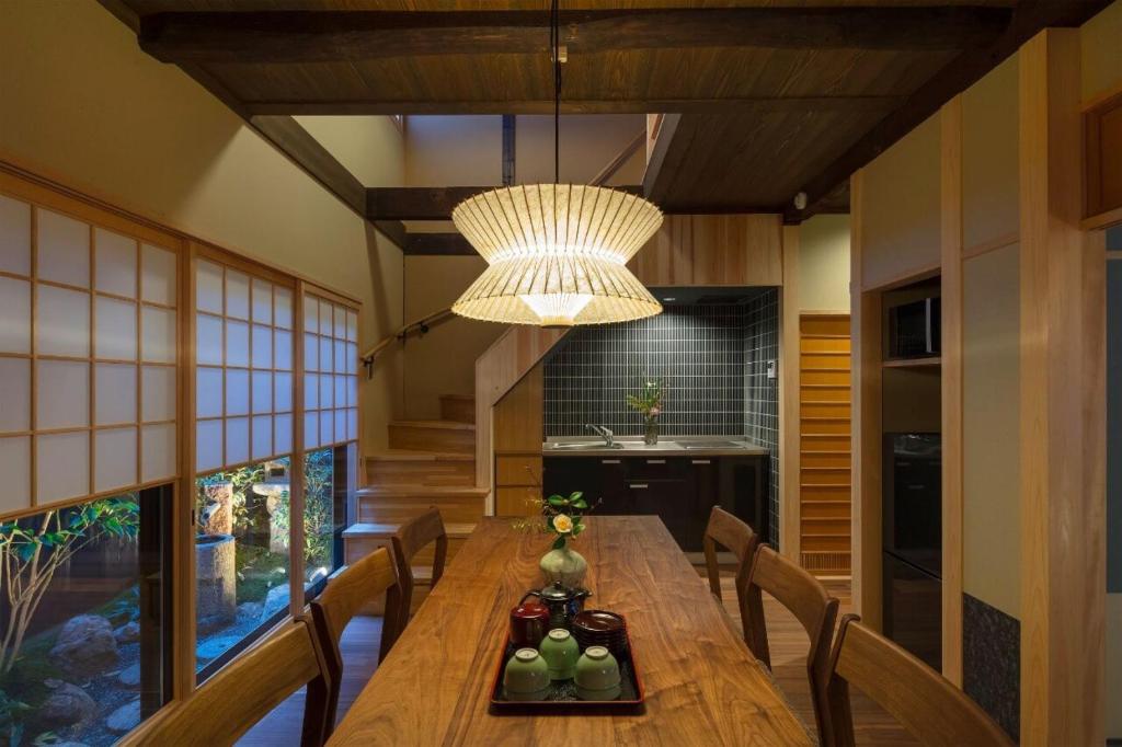 a dining room with a wooden table and a chandelier at Ayaginu Machiya House in Kyoto