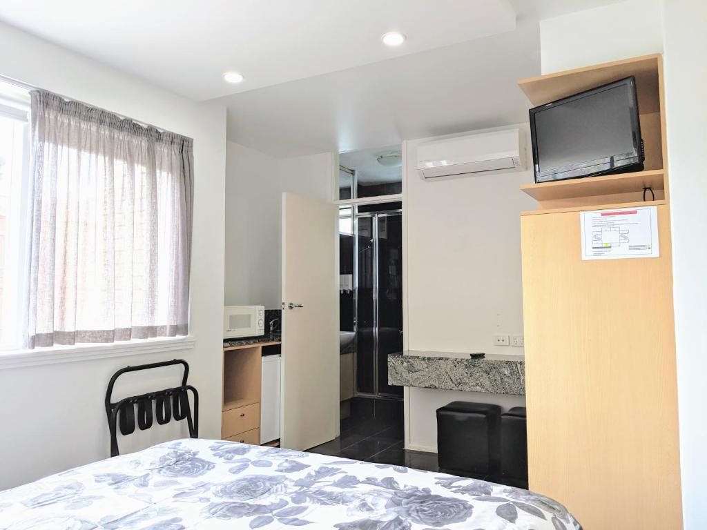 a small room with a bed and a television at Acland Street Studio Apartment FREE PARKING in Melbourne