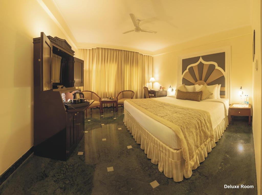 a hotel room with a bed and a flat screen tv at Hotel Clarks Shiraz in Agra