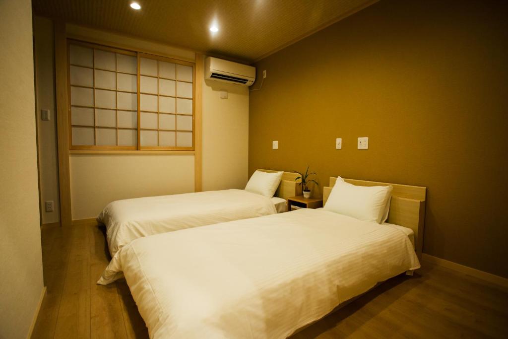 two beds in a small room with a window at Oyado Toshi in Kyoto