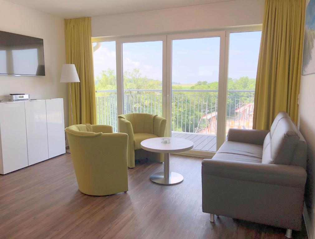 a living room with a couch and chairs and a balcony at FeWo am Meer Schillig-Nordsee 47.4.M in Wangerland