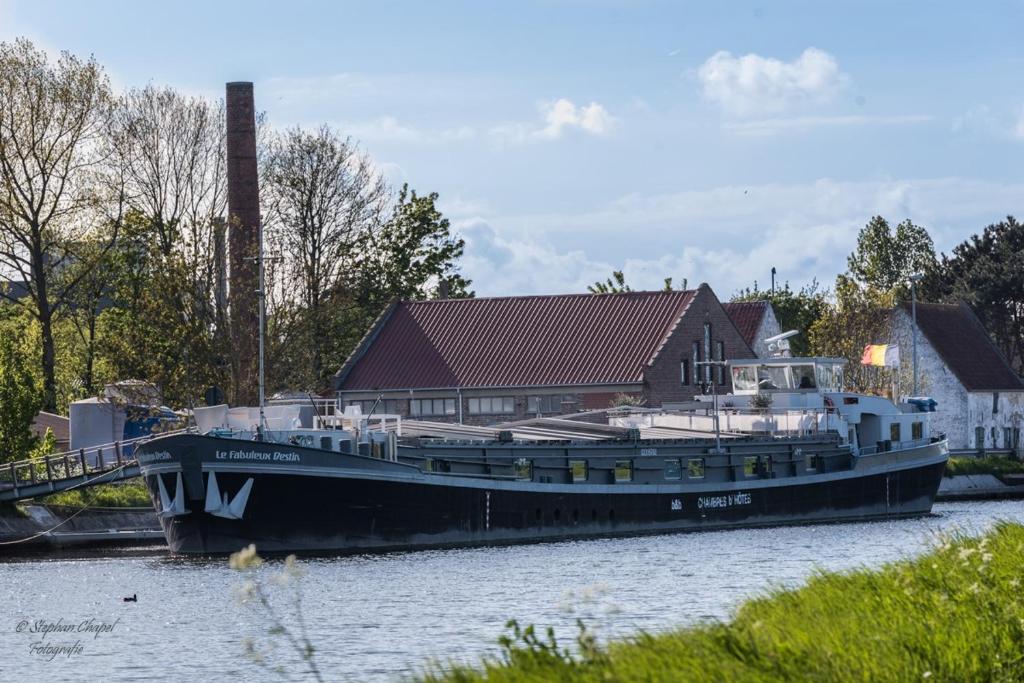 a large boat docked in the water next to a house at B&B Droomboot in Oudenburg