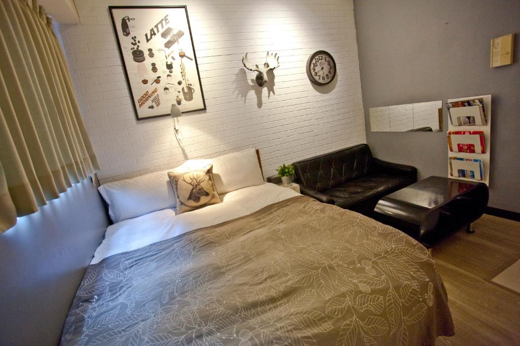 1 dormitorio con 1 cama, 1 silla y 1 reloj en 台中一中街格雷熊, en Taichung