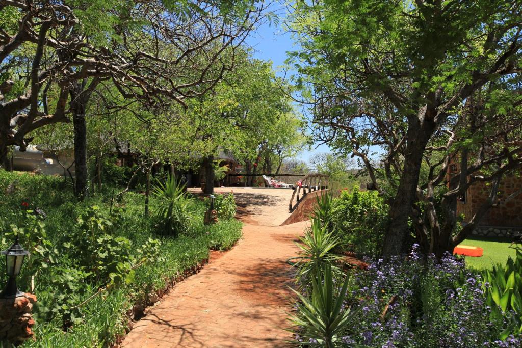 a path through a garden with flowers and trees at Onduri Lodge in Outjo