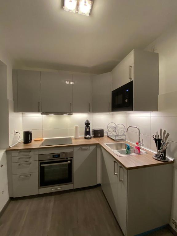 eine Küche mit weißen Schränken und einem Waschbecken in der Unterkunft Apartment in Uninähe in Lübeck