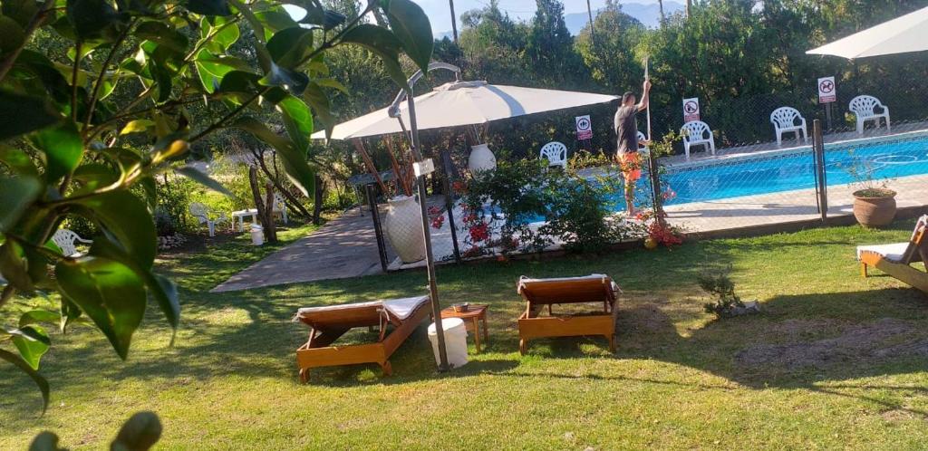 2 sillas y sombrilla junto a la piscina en Cabañas Thijada en Mina Clavero