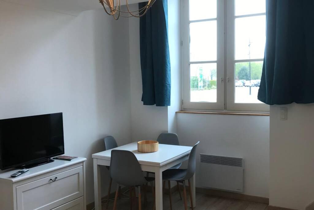 een kleine kamer met een witte tafel en een televisie bij Au pied du phare... in Honfleur