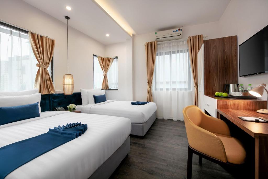Habitación de hotel con 2 camas y escritorio en Patel Hotel Hanoi en Hanoi