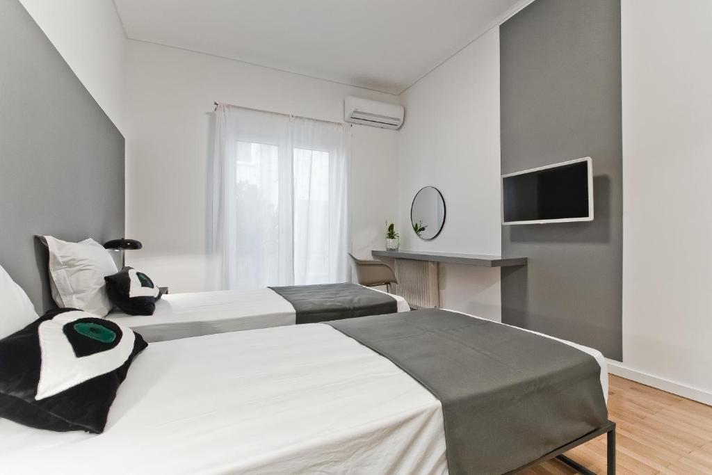 a white bedroom with two beds and a television at BAG- Boutique Apartment Grey - Hilton Area in Athens