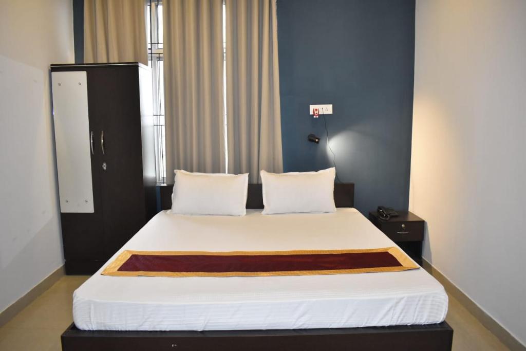 um quarto com uma cama grande e lençóis brancos em Swastik Inn em Guwahati