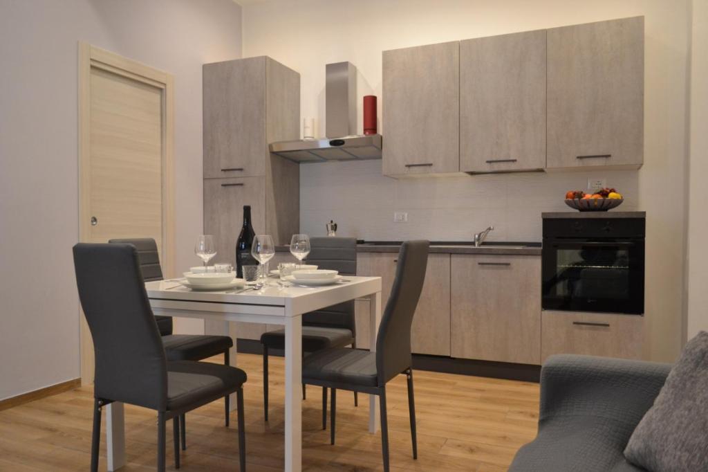 eine Küche mit einem weißen Tisch und Stühlen sowie eine Küche mit Schränken in der Unterkunft Appartamento del Golfo in Castellammare del Golfo