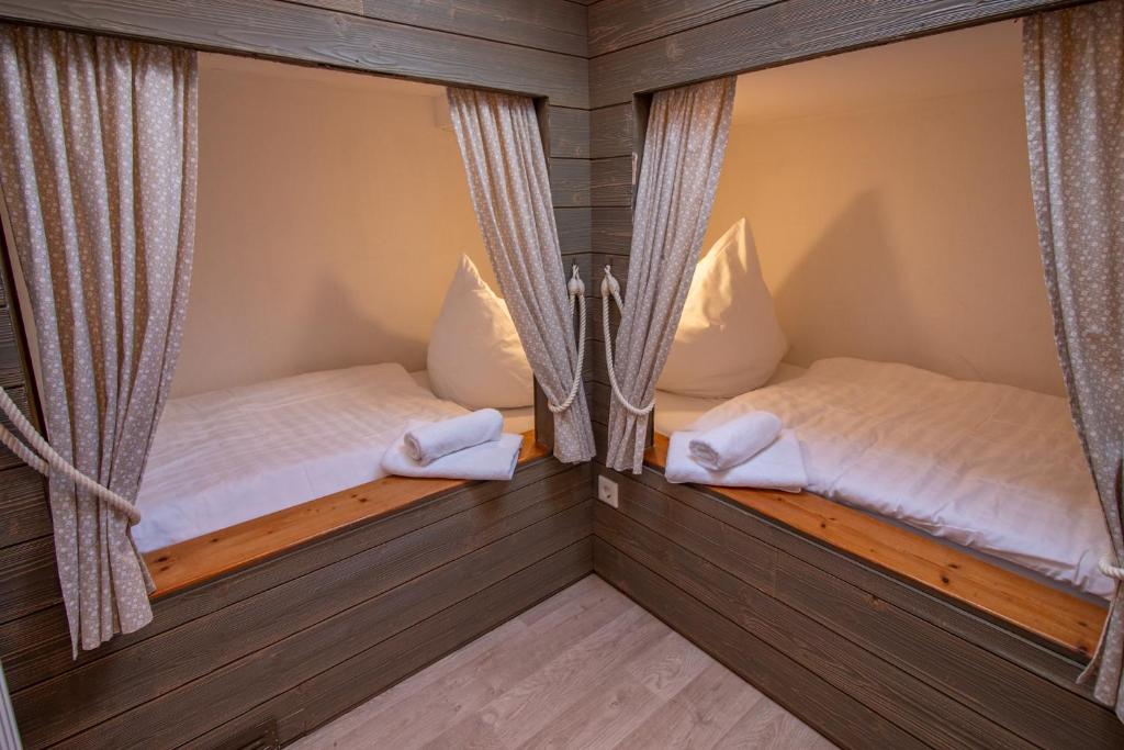 - 2 lits dans une chambre avec des rideaux dans l'établissement Butzenhuuske, à Krummhörn