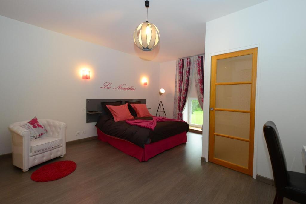 een slaapkamer met een bed, een stoel en een raam bij Le Moulin d'Harcy in Lonny