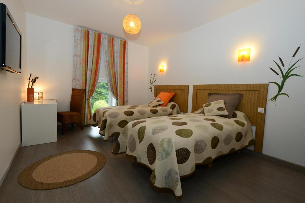 a bedroom with two beds and a television at Le Moulin d'Harcy in Lonny