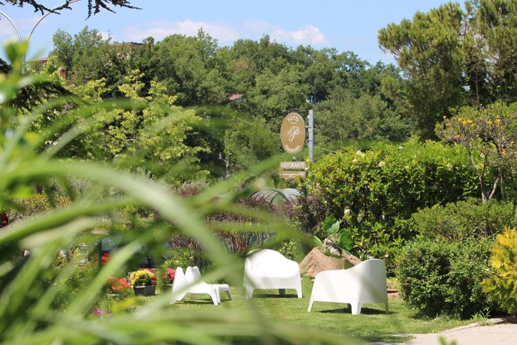 - un ensemble de chaises blanches dans un jardin dans l'établissement Hotel Panorama, à San Valentino in Abruzzo Citeriore