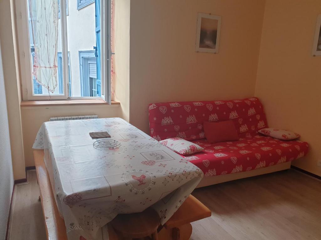 un salon avec une table et un canapé rouge dans l'établissement CAUTERETS, à Cauterets