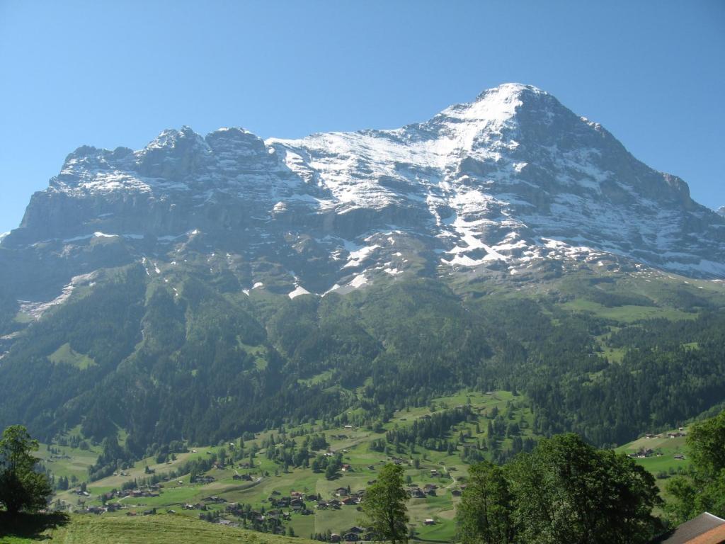 a snow capped mountain with a village in front of it at Chalet uf em Stutz 1 in Grindelwald