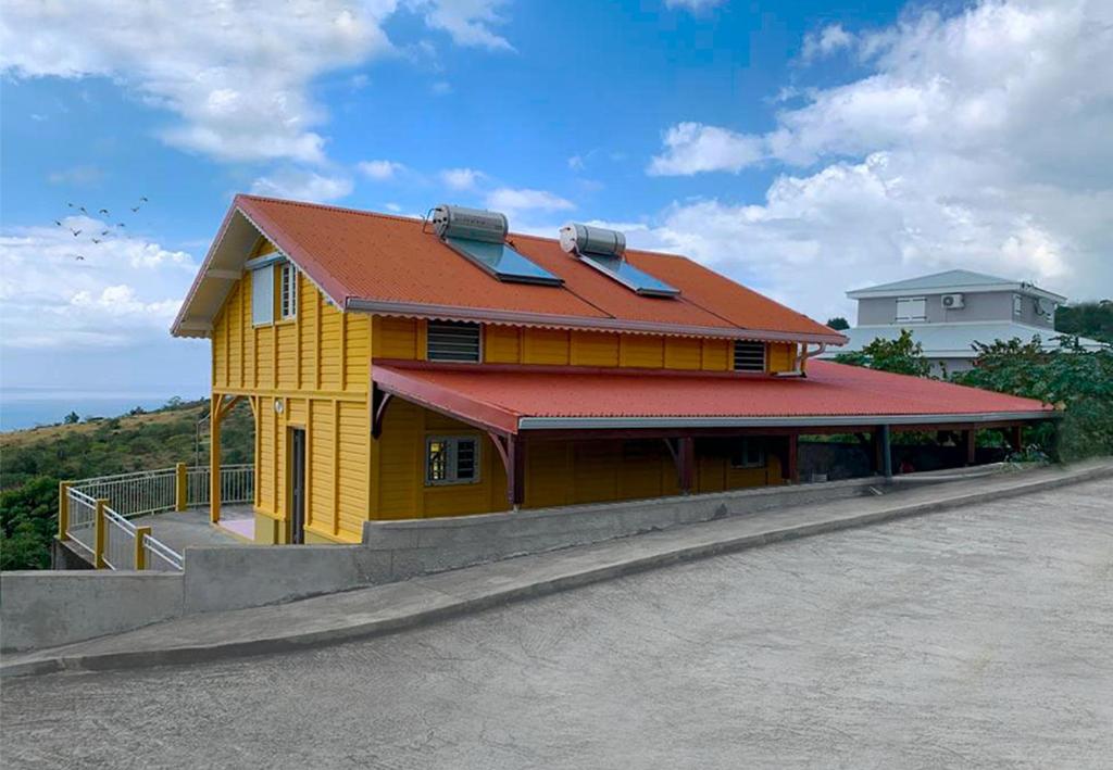 żółty dom z czerwonym dachem na ulicy w obiekcie Le Palma Christi w mieście Le Carbet