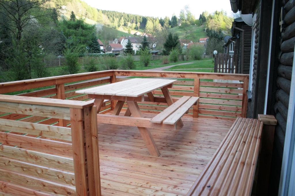 eine Holzterrasse mit einem Picknicktisch und Bänken in der Unterkunft Ferienhäuser Ohratalsperre in Luisenthal