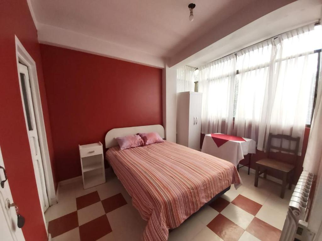 1 dormitorio con cama y pared roja en Residencial Hinojosa, en Oruro