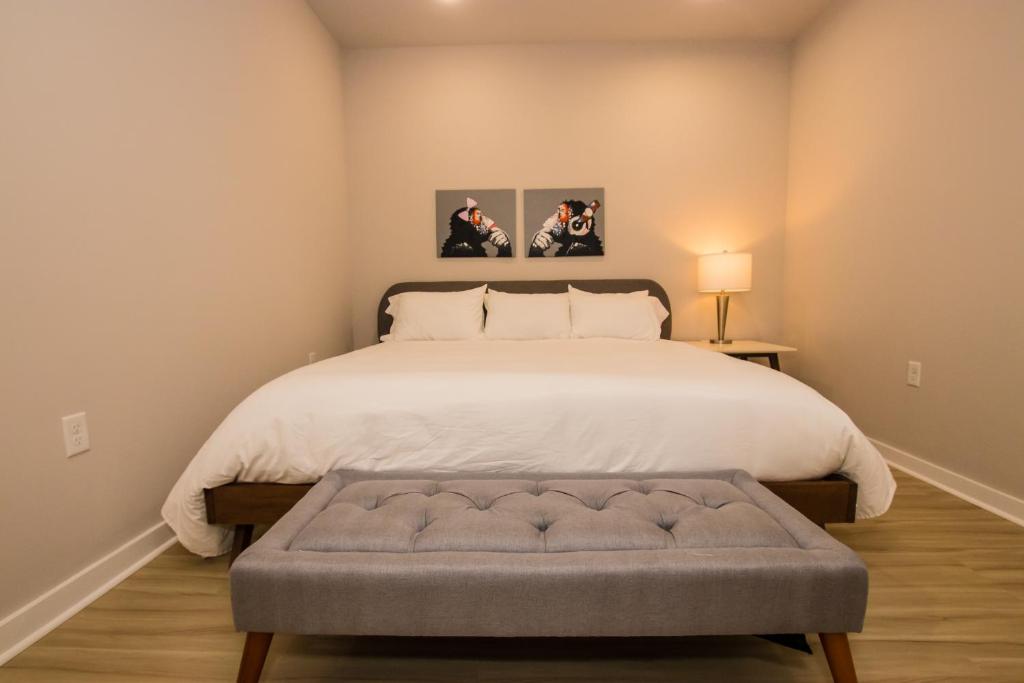 Schlafzimmer mit einem großen weißen Bett und einer Bank in der Unterkunft The Hotel at Huntington Square in Jonesboro