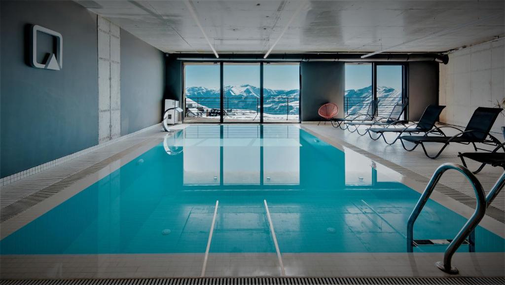 a swimming pool with chairs and a view of mountains at Quadrum Hotel in Gudauri