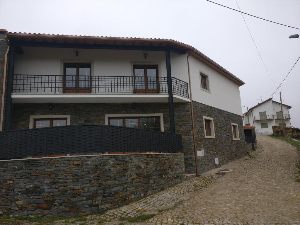 a house with a stone wall and a building at Casa das Olmedas in Vimioso