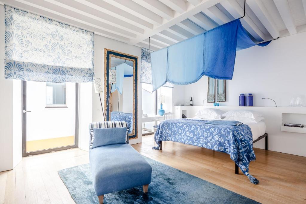 a bedroom with blue curtains and a bed and a chair at Torre de Palma Wine Hotel, Montforte, a Member of Design Hotels in Monforte