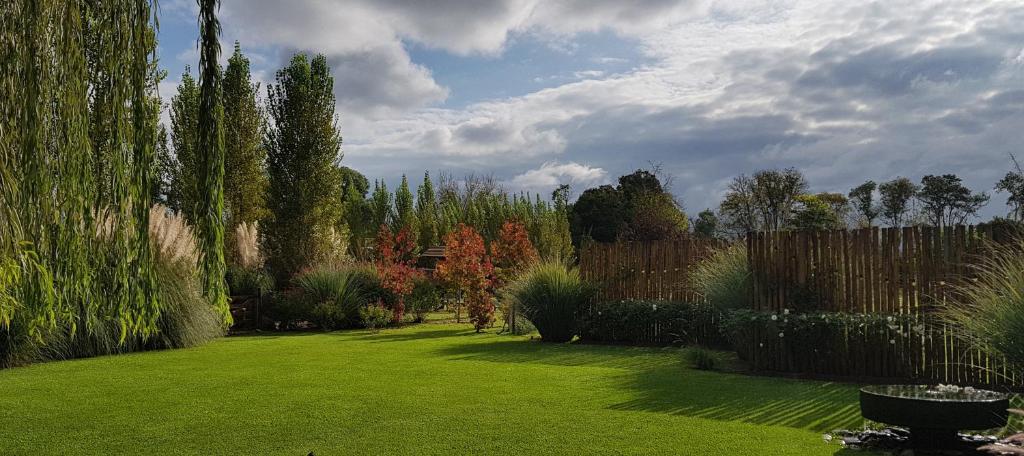 Posada del Santo Green & Rest - Cabañas في سالتا: حديقة بها عشب أخضر وأشجار وسياج