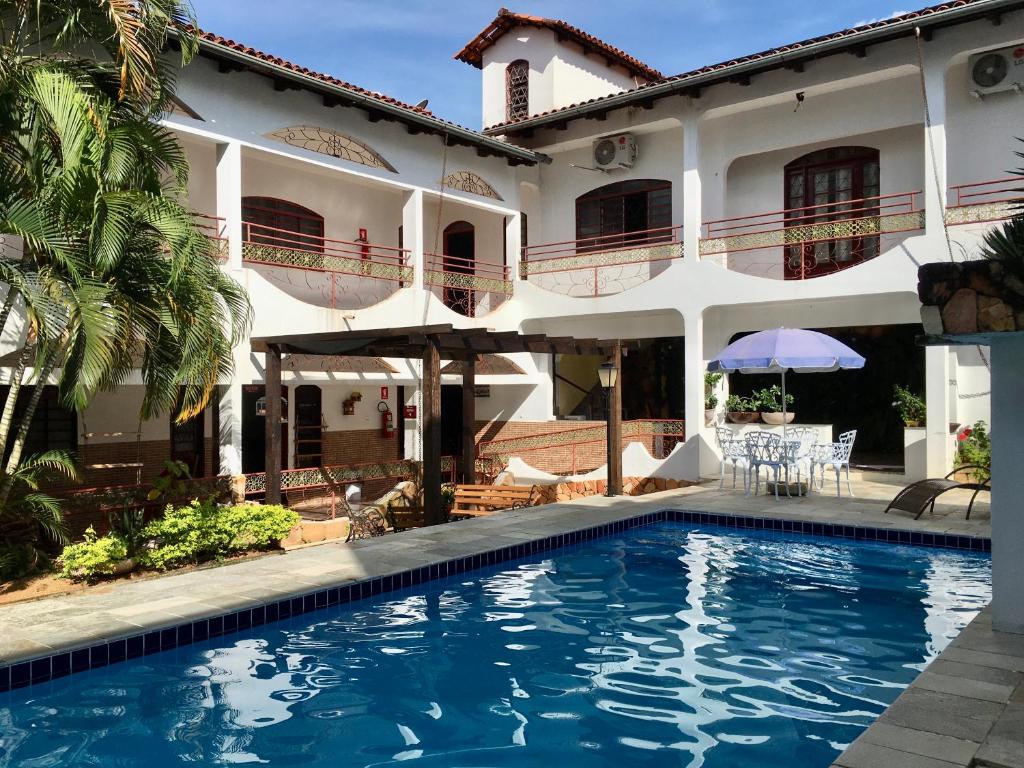 uma villa com piscina em frente a uma casa em Pousada Pollyana em Pirenópolis