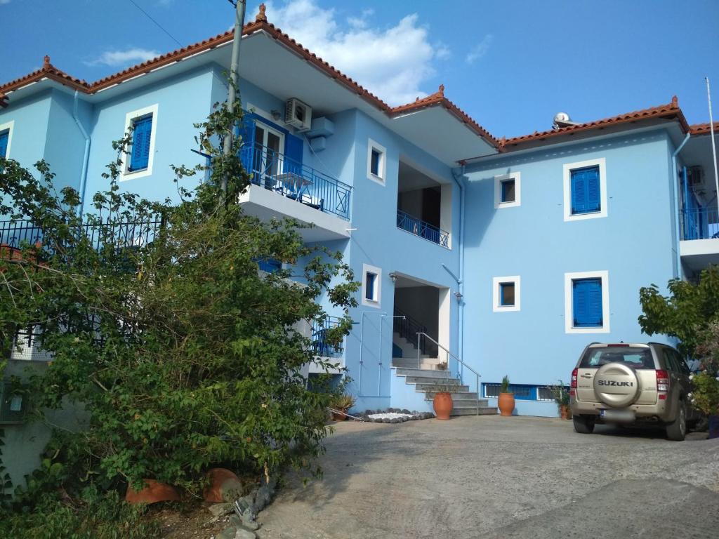 un edificio azul con un coche aparcado delante en Armenaki Apartments, en Sampatiki