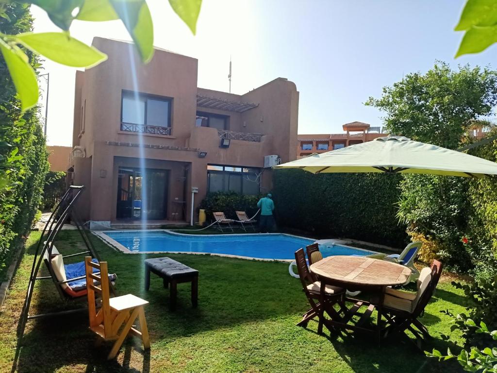 un cortile con tavolo, ombrellone e piscina di Villa with private pool cancun 52 a Ain Sokhna