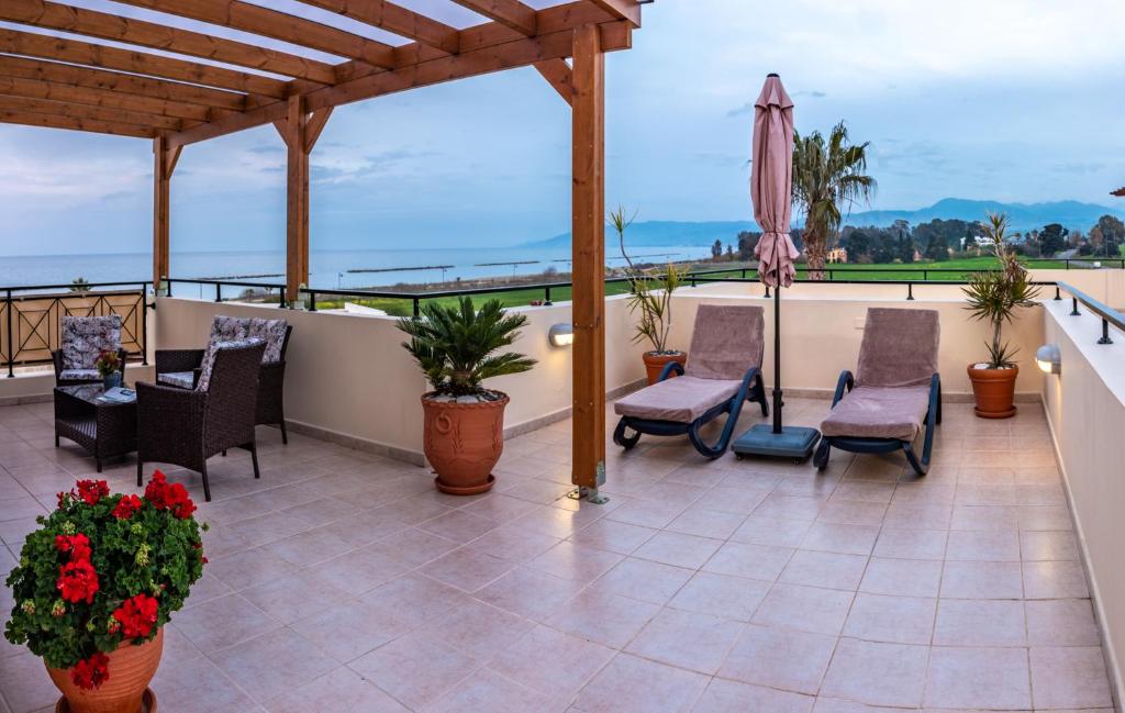 a patio with chairs and an umbrella on a balcony at Penthouse direkt am Meer in Polis Chrysochous