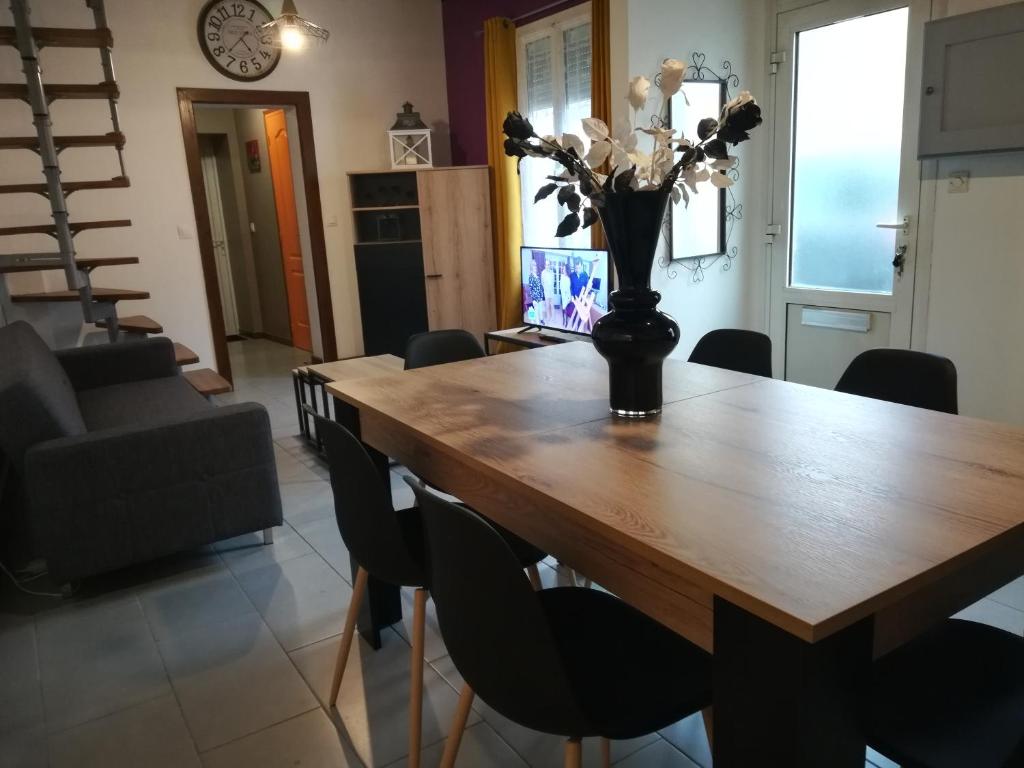 una mesa de comedor con sillas y un jarrón con flores. en Le Loft Montargis Gien maison de ville, en Sainte-Geneviève-des-Bois