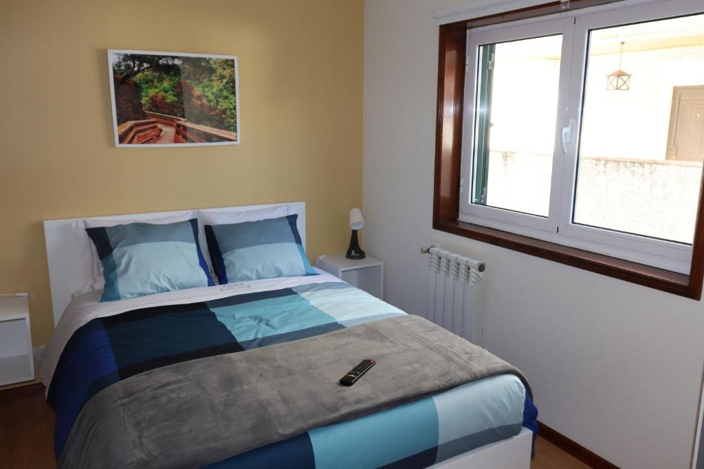 una camera da letto con un letto con cuscini blu e una finestra di Arouca Guest House a Arouca