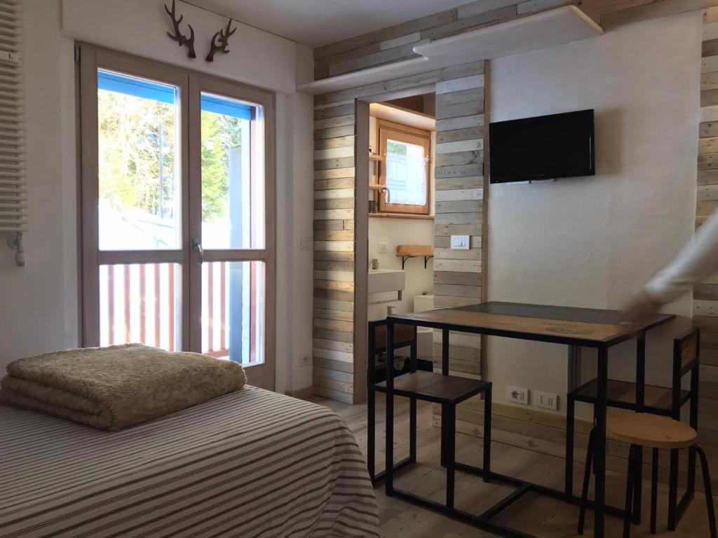 um quarto com uma cama, uma secretária e uma televisão em Appartamento Campiglio em Madonna di Campiglio