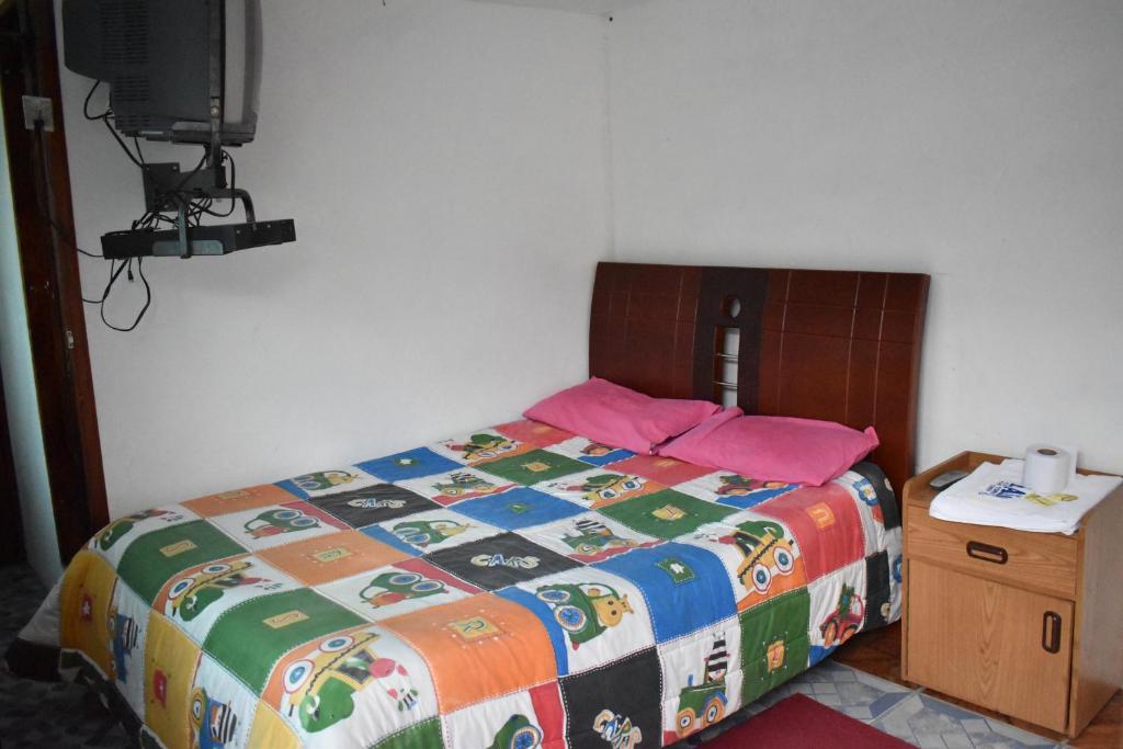 a bedroom with a bed with a colorful comforter at El Aliso - Pujilí in Pujilí