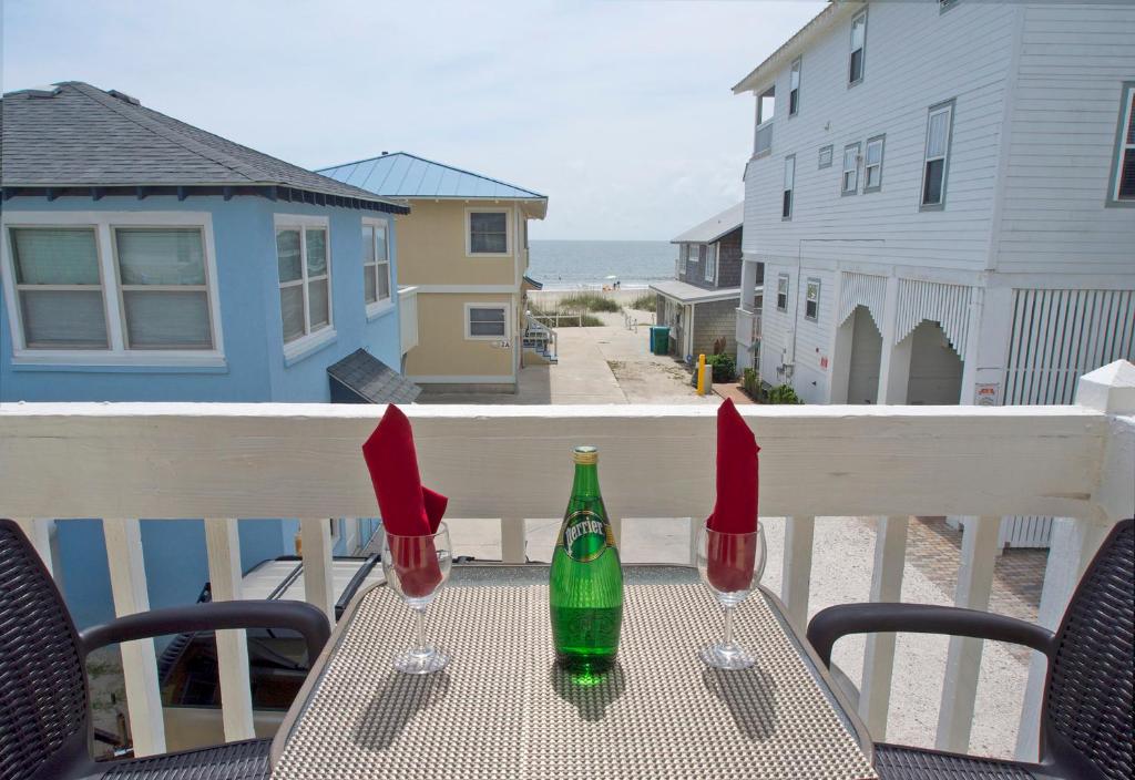 dos copas de vino sentadas en una mesa en un balcón en Tybeeland Steps to the Beach with Oceanviews, Beachside of Butler Ave en Tybee Island