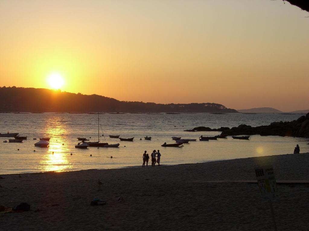 a group of people walking on the beach at sunset at Faro de Aldan in Aldán
