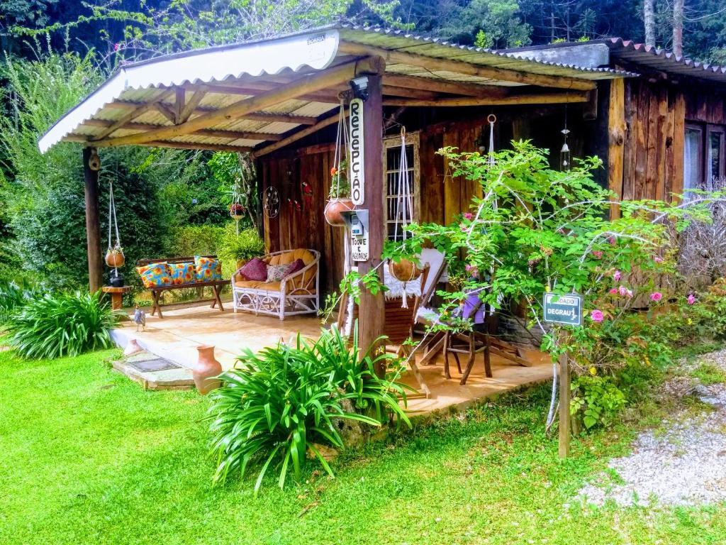 Cabaña pequeña con porche y sillas en un patio en Sitio Vale Piemonte "Chalés ", en Santo Antônio do Pinhal
