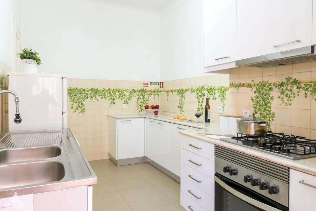 a white kitchen with a sink and a stove at Casa da Avenida Lisboa in Lisbon