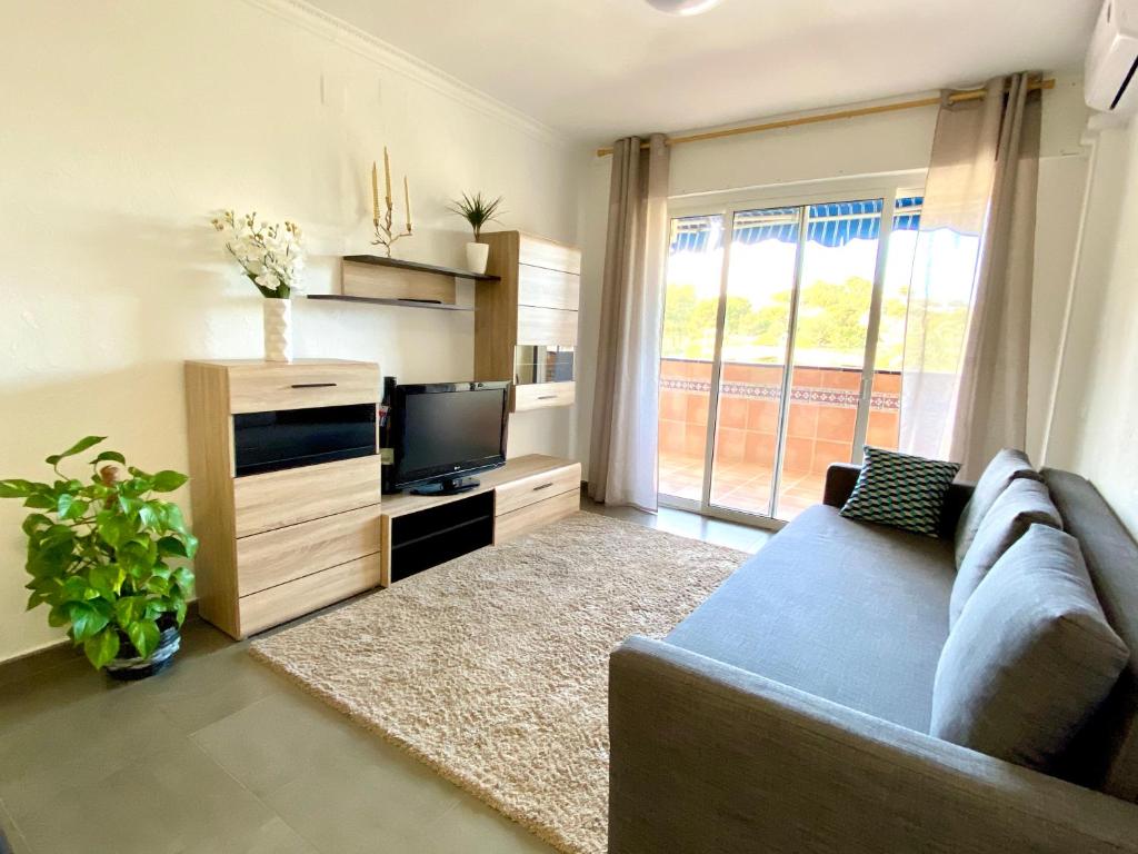 ein Wohnzimmer mit einem Sofa und einem TV in der Unterkunft Excelente apartamento in La Pineda