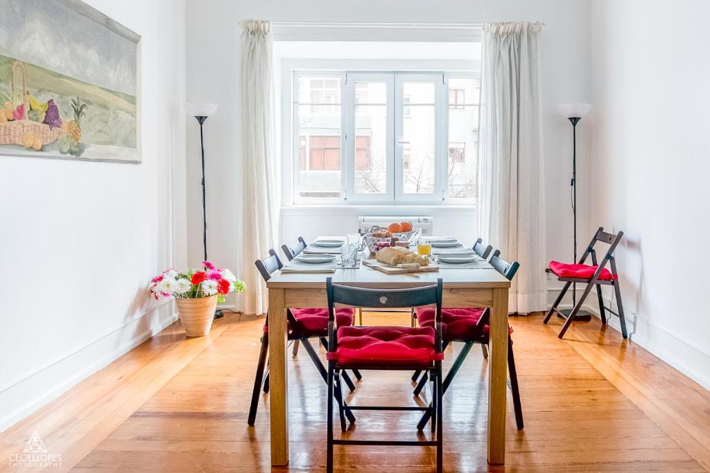 a dining room with a table with red chairs at Casa da Avenida Lisboa in Lisbon