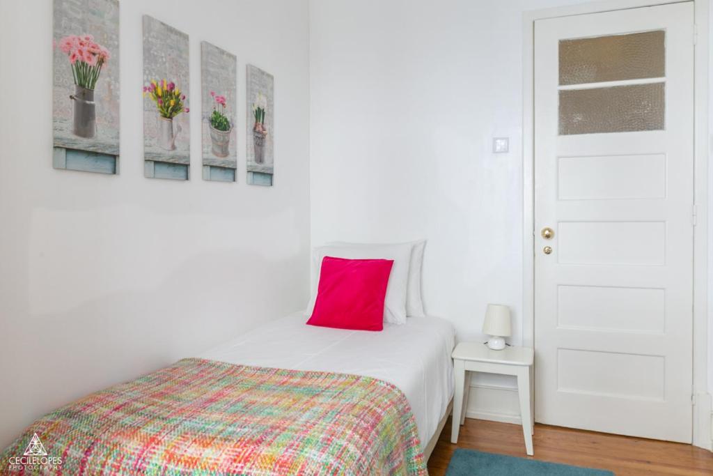 a bedroom with a bed with a red pillow on it at Casa da Avenida Lisboa in Lisbon