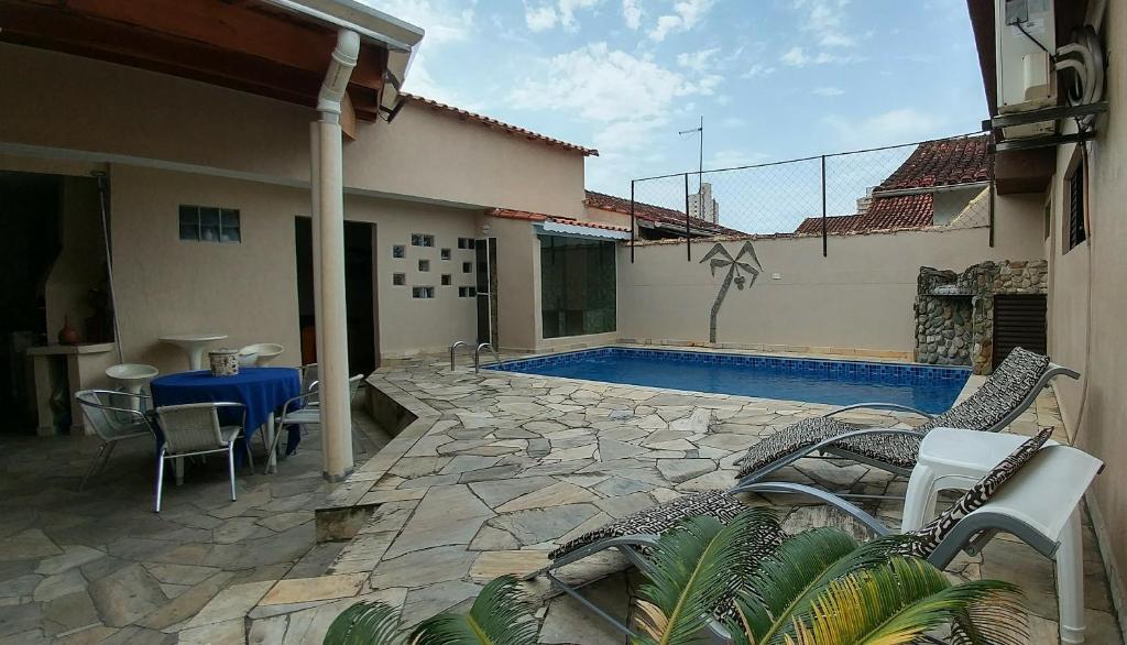 a patio with a table and chairs and a swimming pool at Casa de Férias Praia Grande in Praia Grande