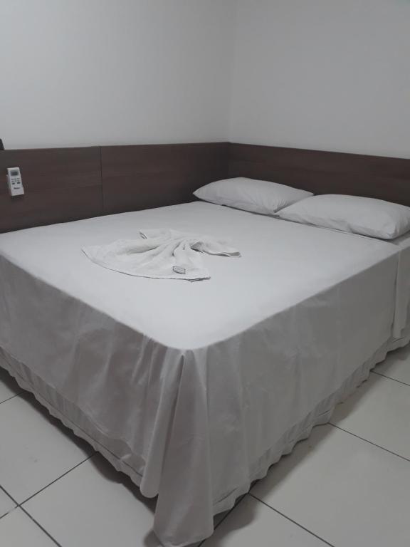 Una cama con sábanas blancas y almohadas blancas. en Pousada Pampa Gaúcho, en Teresina