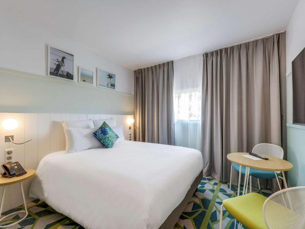 a bed room with a white bedspread and a white comforter at Mercure Paris Orly Tech Airport in Orly